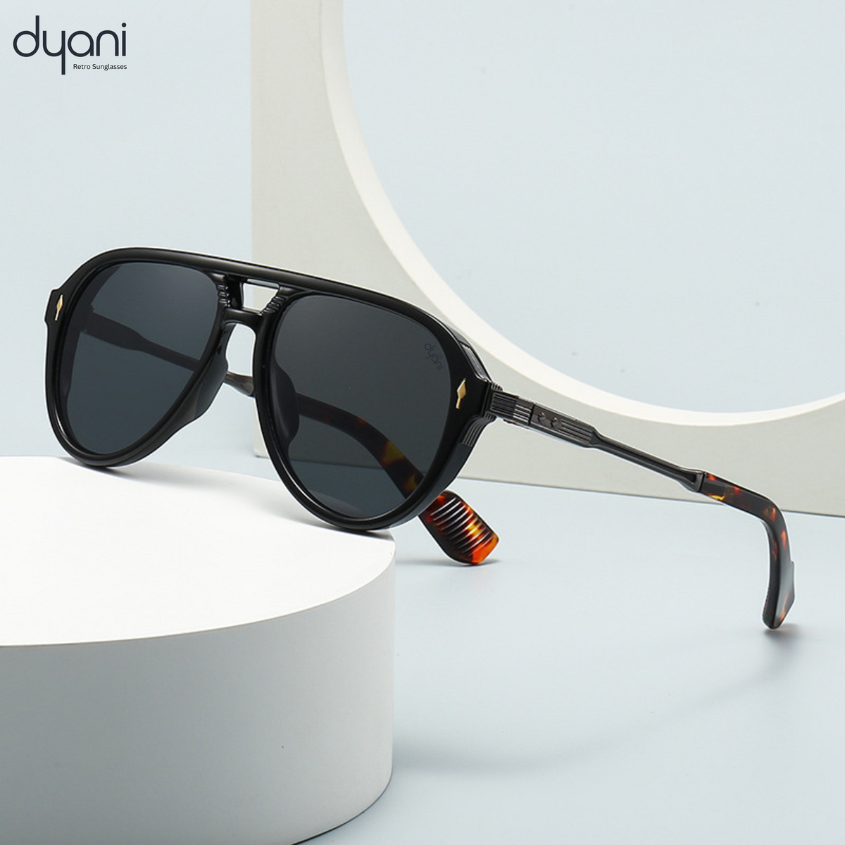 Dyani The Sovereign aviator sunglasses with sleek black lenses, white temples, and bold modern half-frame design, on light backdrop.