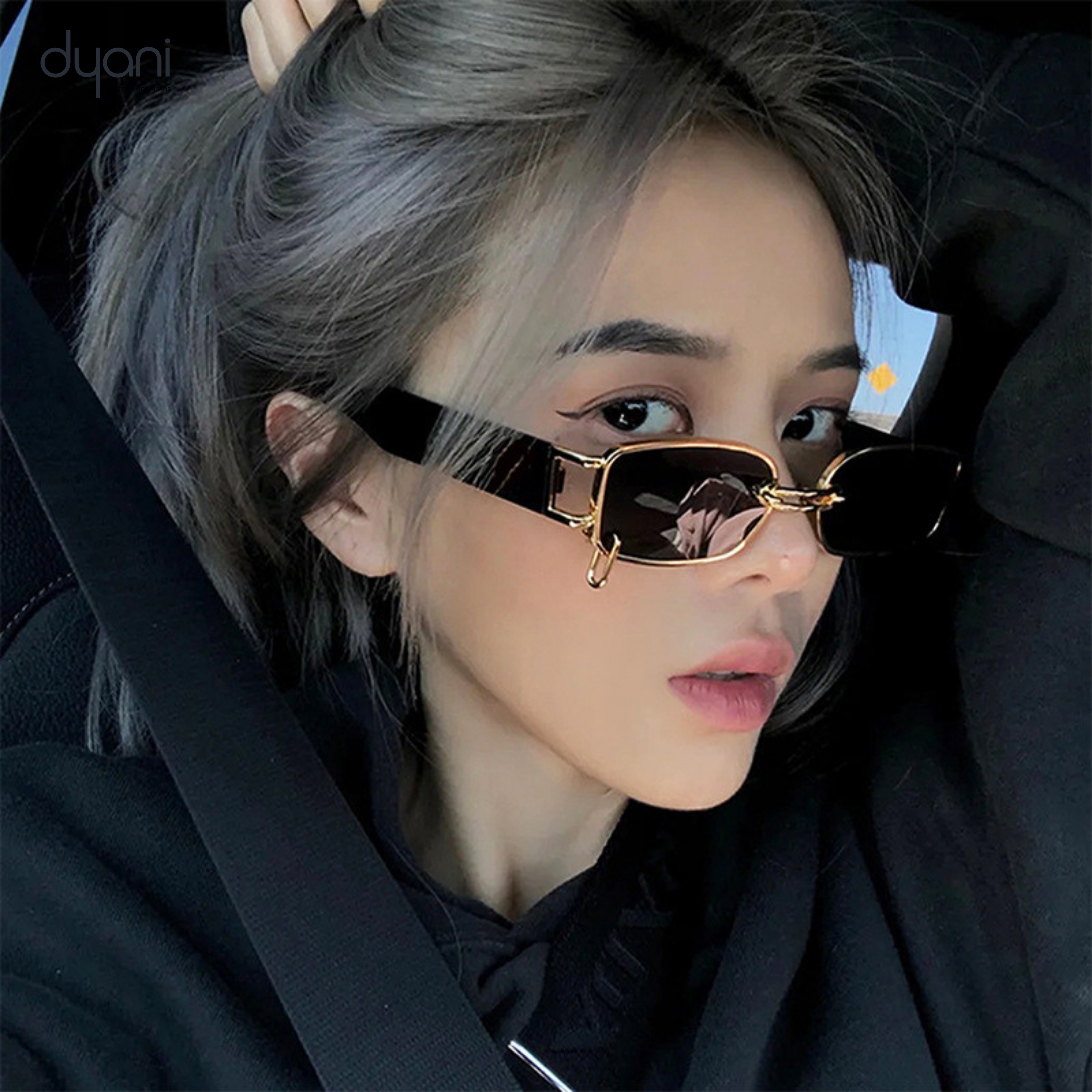 Person wearing The Rebel sunglasses with gold chain-link bridge, rectangular lenses, and wide black arms for a stylish look.