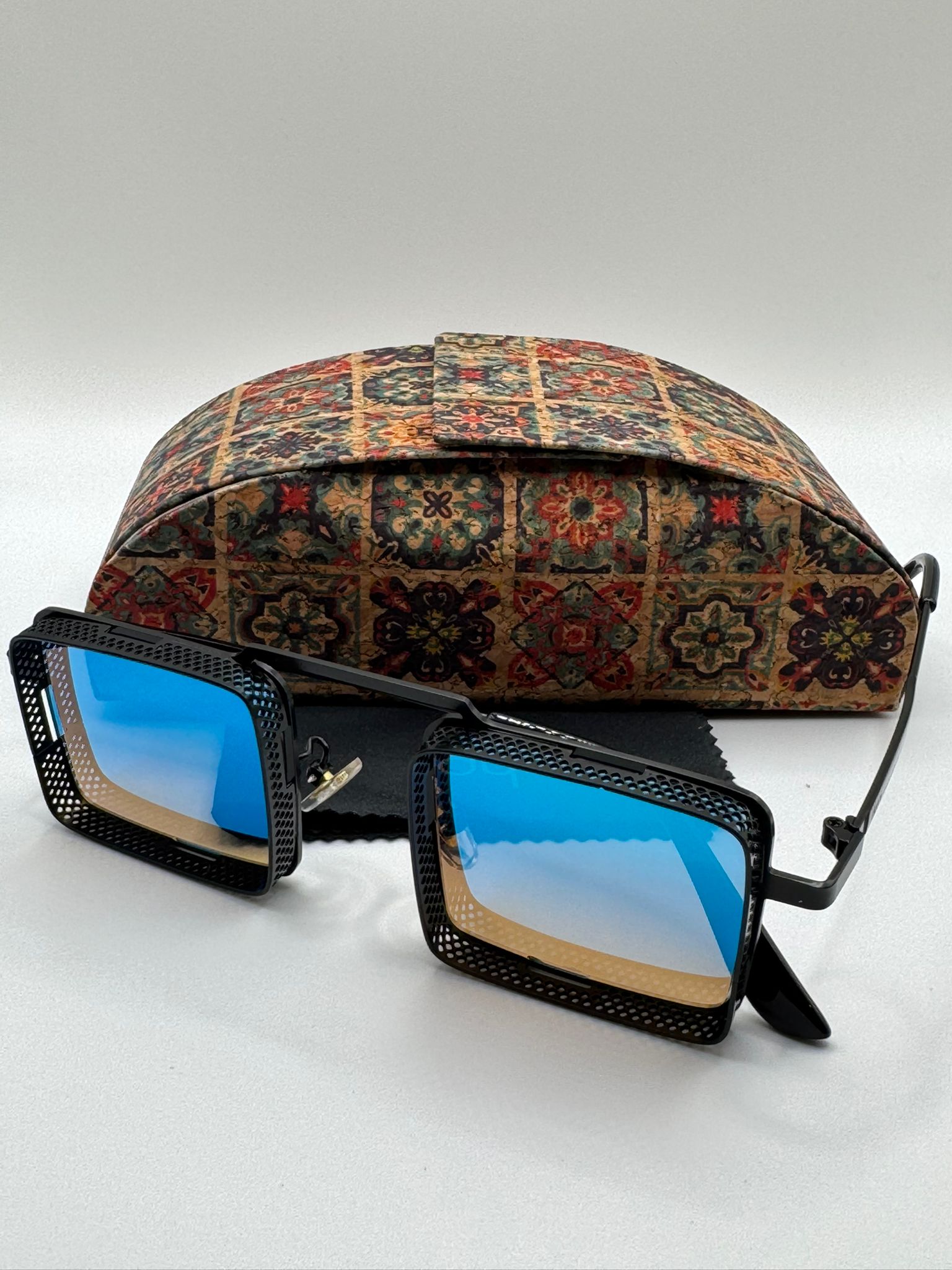 Dyani Square Punk sunglasses with blue lenses and steampunk design, featuring strong aluminum magnesium frame, with case in the background.