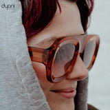 Person wearing Velora bold acetate sunglasses with rounded frames and gradient lenses by Dyani.